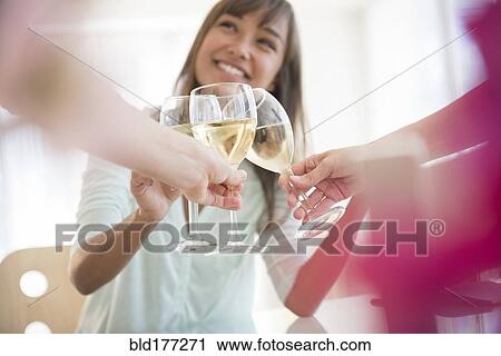 Stock Image - Friends toasting with white wine. Fotosearch