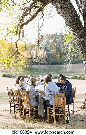Picture - Friends toasting with wine at outdoor table. Fotosearch