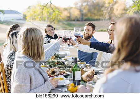 Friends toasting with wine at outdoor table View Large Photo Image Stock Image - Friends toasting with wine at outdoor table. Fotosearch
