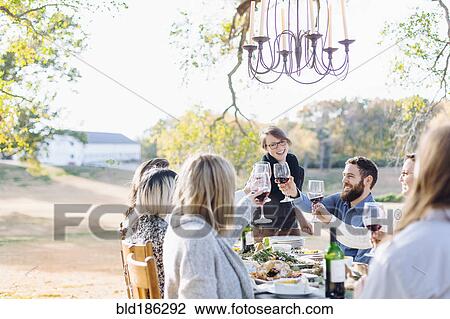 Friends toasting with wine at outdoor table View Large Photo Image Stock Image - Friends toasting with wine at outdoor table. Fotosearch