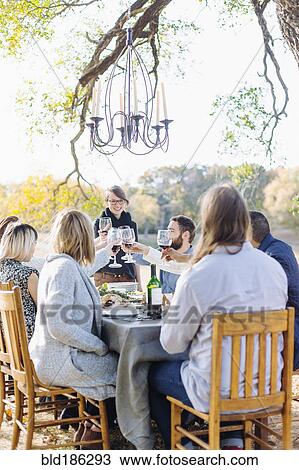 Stock Image - Friends toasting with wine at outdoor table. Fotosearch