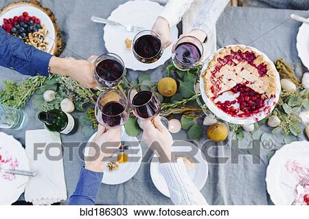 Stock Image - Friends toasting with wine at outdoor table. Fotosearch