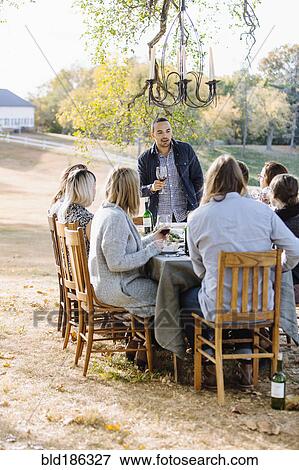 Stock Photo - Friends toasting with wine at outdoor table. Fotosearch