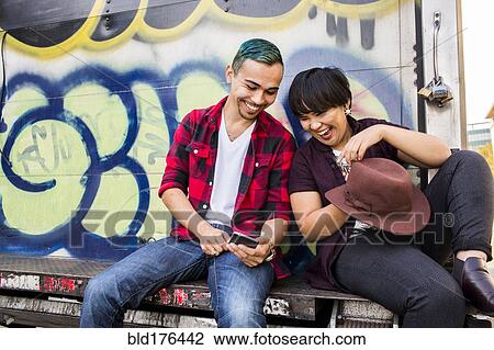Friends using cell phone on graffiti truck View Large Photo Image Stock Image - Friends using cell phone on graffiti truck. Fotosearch