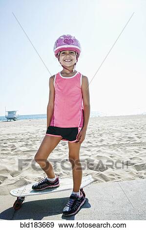 Stock Photo - Girl riding skateboard at beach. Fotosearch