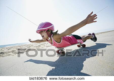Stock Photograph - Girl riding skateboard at beach. Fotosearch