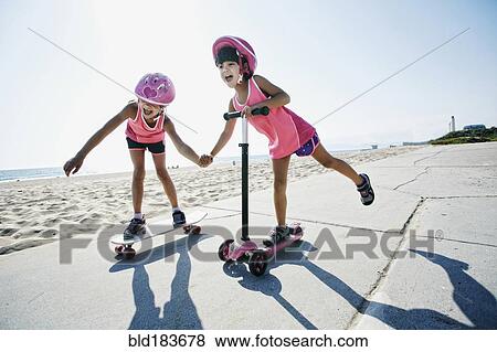 Girls riding skateboard and scooter at beach View Large Photo Image Stock Photo - Girls riding skateboard and scooter at beach. Fotosearch