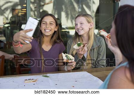 Stock Image - Girls taking selfie in cafe. Fotosearch