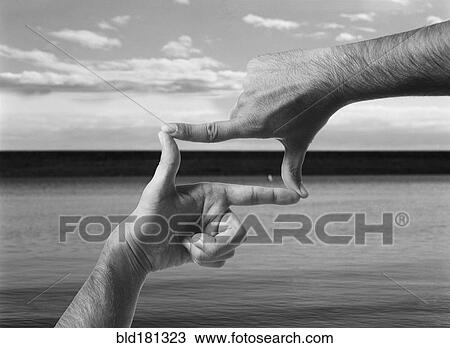 Stock Image - Hands forming frame shape over ocean. Fotosearch