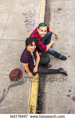 Stock Photo - High angle view of couple sitting on curb. Fotosearch