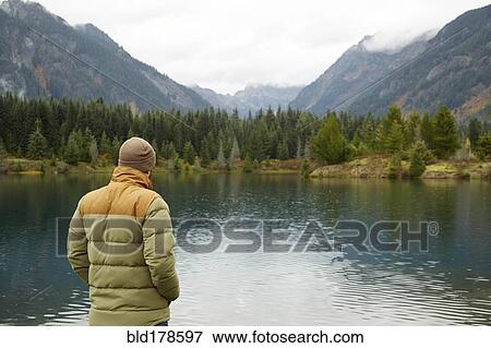 Stock Photo - Hiker admiring lake and remote landscape. Fotosearch