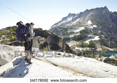 Stock Image - Hikers standing on rocky hilltop. Fotosearch