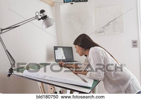 Stock Image - Hispanic architect drawing at drafting table. Fotosearch