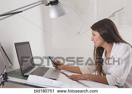 Stock Image - Hispanic architect working at drafting table. Fotosearch