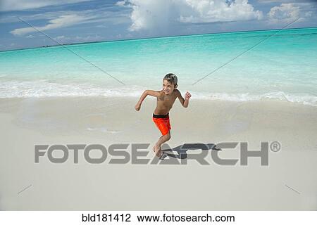 Stock Image - Hispanic boy running on beach. Fotosearch