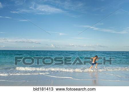 Stock Image - Hispanic boy running on beach. Fotosearch