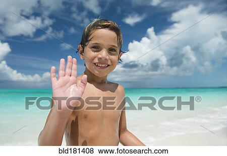Stock Photo - Hispanic boy waving on beach. Fotosearch