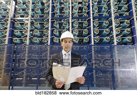 Stock Photo - Hispanic businessman reading folder in power plant. Fotosearch