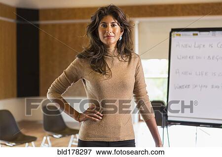 Stock Photo - Hispanic businesswoman standing in meeting room. Fotosearch