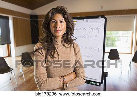 Stock Photograph - Hispanic businesswoman standing in meeting room. Fotosearch