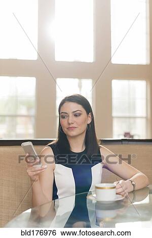 Stock Photograph - Hispanic businesswoman using cell phone in office. Fotosearch