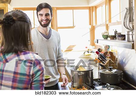 Stock Image - Hispanic couple cooking in kitchen. Fotosearch