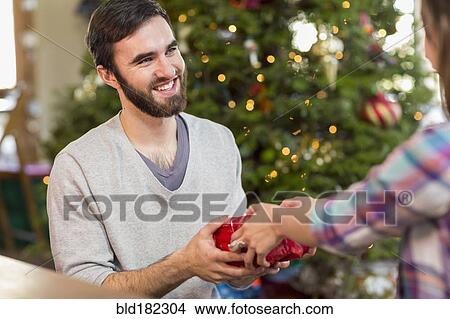 Picture - Hispanic couple exchanging Christmas gifts. Fotosearch