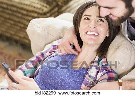 Hispanic couple using cell phone on sofa View Large Photo Image Stock Photo - Hispanic couple using cell phone on sofa. Fotosearch