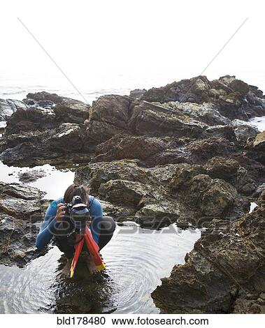 Stock Image - Hispanic diver photographing on beach. Fotosearch