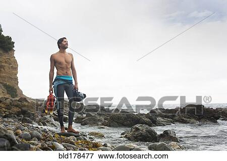 Stock Photo - Hispanic diver wearing wetsuit on beach. Fotosearch