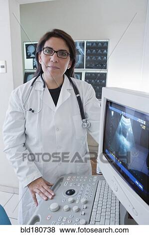Stock Photo - Hispanic doctor examining sonogram in hospital. Fotosearch