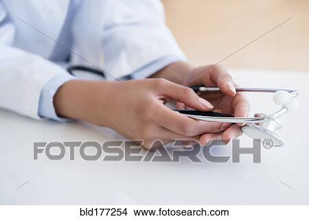 Picture - Hispanic doctor holding stethoscope. Fotosearch
