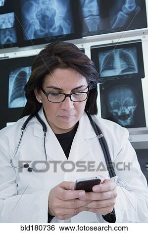 Hispanic doctor using cell phone in hospital View Large Photo Image Stock Photograph - Hispanic doctor using cell phone in hospital. Fotosearch