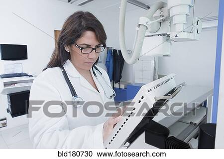 Stock Image - Hispanic doctor using x-ray in hospital. Fotosearch