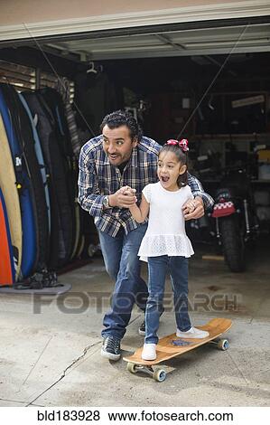 Hispanic father teaching daughter to ride skateboard View Large Photo Image Stock Photo - Hispanic father teaching daughter to ride skateboard. Fotosearch