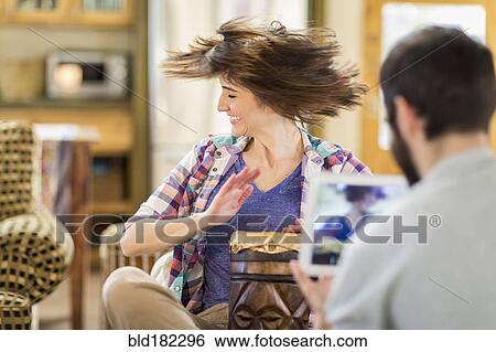 Stock Photograph - Hispanic man recording girlfriend playing drums. Fotosearch
