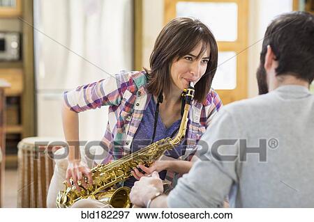 Stock Photo - Hispanic man watching girlfriend playing saxophone. Fotosearch