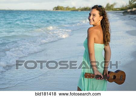 Stock Photo - Hispanic teenage girl holding ukulele on beach. Fotosearch