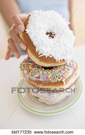 Stock Photography - Hispanic woman choosing donut. Fotosearch