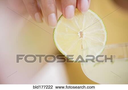 Stock Image - Hispanic woman garnishing cocktail. Fotosearch