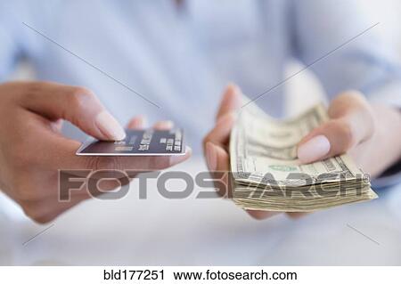 Stock Image - Hispanic woman holding cash and credit card. Fotosearch