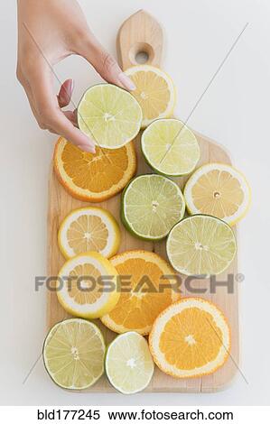 Stock Photography - Hispanic woman holding sliced lime. Fotosearch
