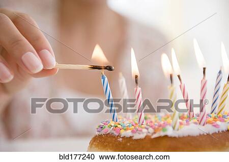 Stock Image - Hispanic woman lighting birthday candles. Fotosearch