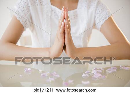 Stock Image - Hispanic woman meditating at table. Fotosearch