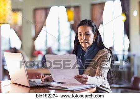 Hispanic woman paying bills on laptop in cafe View Large Photo Image Picture - Hispanic woman paying bills on laptop in cafe. Fotosearch