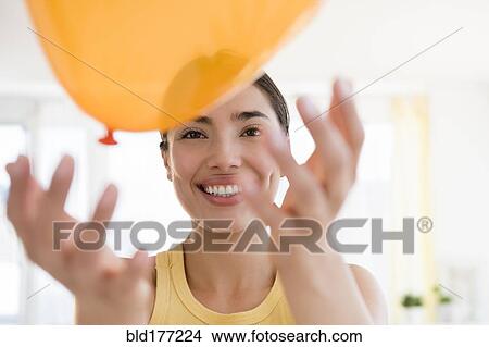 Picture - Hispanic woman playing with balloon. Fotosearch
