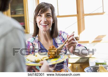 Hispanic woman serving boyfriend in kitchen View Large Photo Image Stock Image - Hispanic woman serving boyfriend in kitchen. Fotosearch