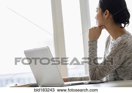 Stock Image - Hispanic woman sitting at laptop. Fotosearch