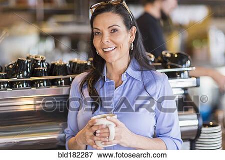 Stock Photo - Hispanic woman smiling in coffee shop. Fotosearch