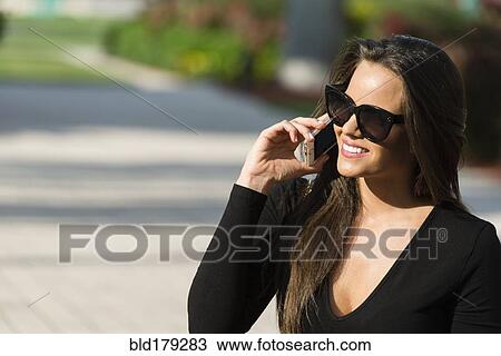 Stock Image - Hispanic woman talking on cell phone. Fotosearch